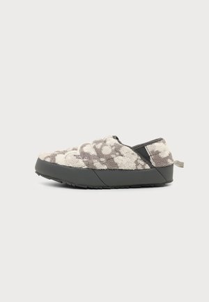 Chaussure slip-on profil bas avec empeigne texturée grise et blanche, semelle noire et languette au talon, vue de côté sur fond blanc.