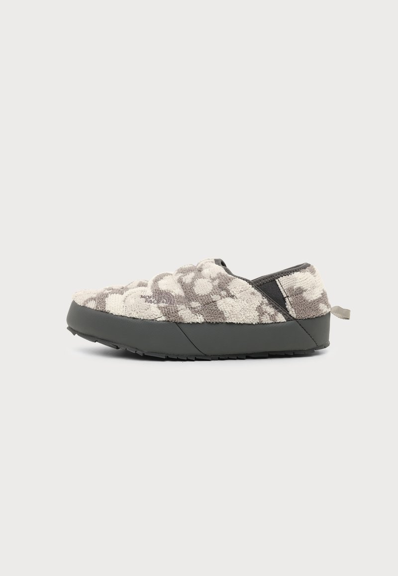 Παπούτσι slip-on με χαμηλό προφίλ, γκρι και λευκό υφασμάτινο επάνω μέρος, μαύρη σόλα και ταινία στο πίσω μέρος, εμφανιζόμενο από το πλάι σε λευκό φόντο.