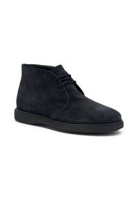 Botines de ante negros con punta redonda, diseño minimalista de cordones y superficie texturizada, que cuentan con una suela de goma para mayor tracción.