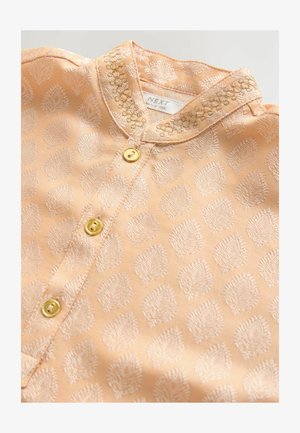Camicia in tessuto pesca chiaro con motivi a foglia ricamati, bottoni dorati lucidi e un colletto decorativo con cuciture intricate.