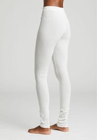 Leggings bianchi aderenti realizzati in tessuto testurizzato con un motivo sottile. Presentano una vita elasticizzata e un design a gamba affusolata.