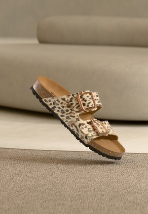 Leopard print two-strap sandal with a cushioned footbed, brown sole, and adjustable metal buckles. Textured upper and rubber outsole.