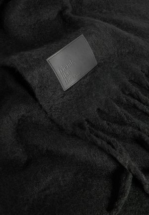 Manta de lana negra con una textura suave y un parche de cuero grabado con la frase "amigos como estos..." y detalles de flecos.