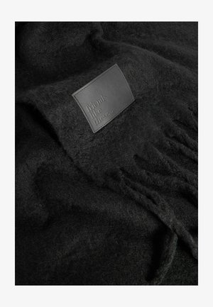 Juodas vilnonis pledas su minkšta tekstūra ir odiniu užspaustu ženklu „tokie draugai...“ bei kutais.