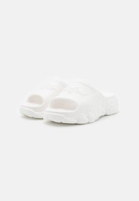 Chanclas blancas de goma texturizada. Diseño de punta abierta con suela redondeada y logo elevado en la correa superior. Acabado suave.
