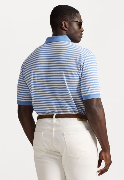 Camisa polo riscada em azul claro e branco com colarinho, usada com calças brancas e um cinto castanho. Tecido texturizado e mangas curtas.