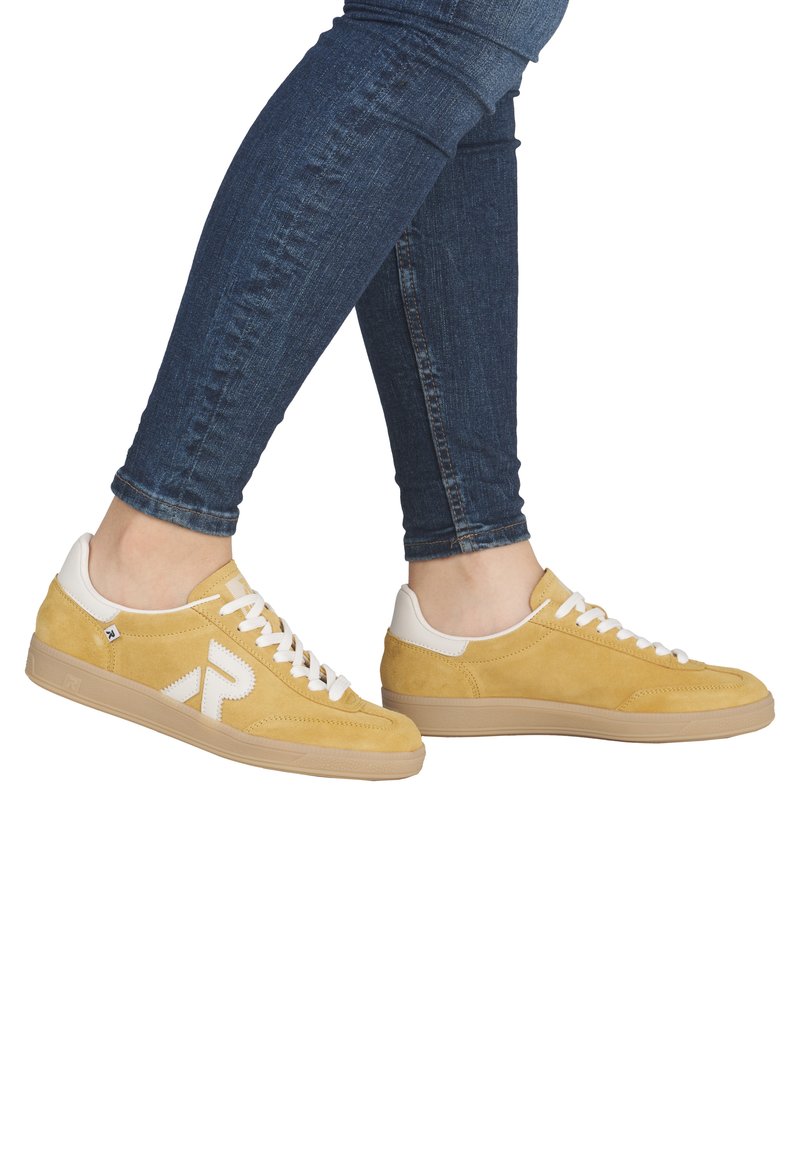 Baskets en daim jaune avec des accents blancs, présentant une surface texturée, une fermeture à lacets et une semelle en caoutchouc marron clair.