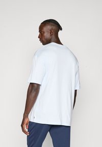Lys blå, kortærmet t-shirt lavet af bomuld. Har en afslappet pasform og en rund halsudskæring, med diskrete sidespalter i kanten.