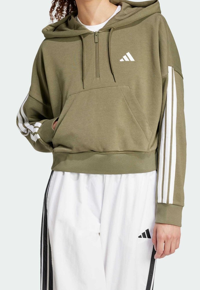 Olivgrön kort hoodie i mjukt material, med dragkedja framtill, en kenguruficka och vita tre-stripes detaljer på ärmarna.