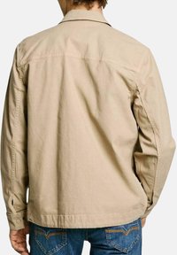 Camicia di cotone beige con colletto e maniche lunghe, con cuciture in vista, polsini abbottonati e orlo dritto.