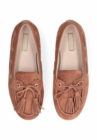 Mocassins en daim marron avec des pampilles, des coutures décoratives et des œillets dorés. Bout arrondi et doublure intérieure douce.