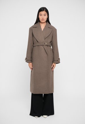 Brown wool trench coat featuring a large collar, belted waist, and wide sleeves. Paired with black wide-leg pants and white pointed shoes.