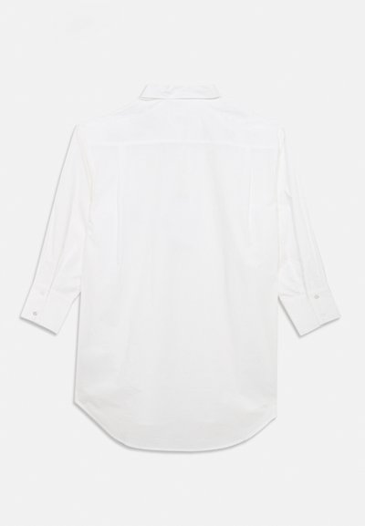Λευκό πουκάμισο με μακριά μανίκια, πίσω γιακά, μανσέτες με κουμπιά και καμπυλωτό τελείωμα. Το ύφασμα φαίνεται λείο με διακριτική λάμψη.