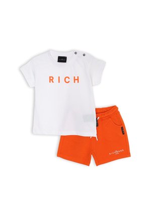 T-shirt bianca con testo arancione "RICH", maniche corte, abbinata a pantaloni corti arancioni con tasche laterali e vita con cordino.
