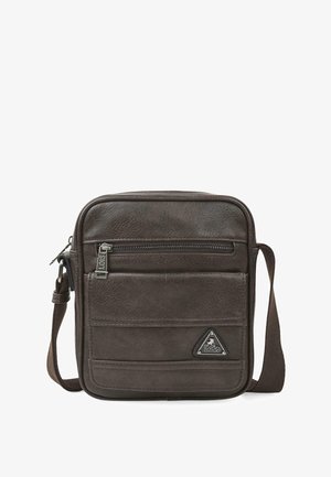 Bolso mensajero de cuero marrón con correa ajustable, bolsillo frontal con cremallera y parche de logo. Presenta una textura suave y forma rectangular.