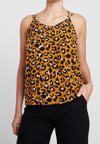Caraco imprimé léopard avec bretelles réglables, présentant un fond orange avec des taches noires et roses. Tissu léger et texturé, coupe décontractée.