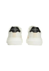 Sneakers bianchi con suola testurizzata, accenti beige sui lati e un tab di tallone nero con marchio "Calvin Klein Jeans".