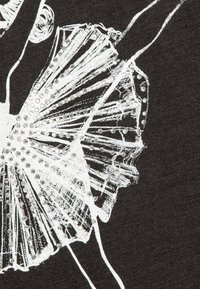 Sort stof med en hvid balletdanserillustration, der har en plisseret tutu, der er detaljeret med små, blanke rhinsten over designet.