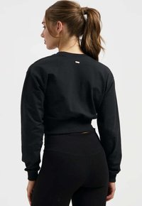 Schwarzer, kurzer Sweatshirt mit langen Ärmeln, gerippten Bündchen und Saum, mit einem kleinen Logodetail am Nacken hinten. Weiche Stoffstruktur.