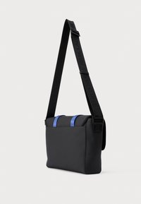 Juoda stačiakampio formos per petį nešiojama rankinė su reguliuojama rankena ir dviem mėlynais akcentais viršuje ant vientiso fono.