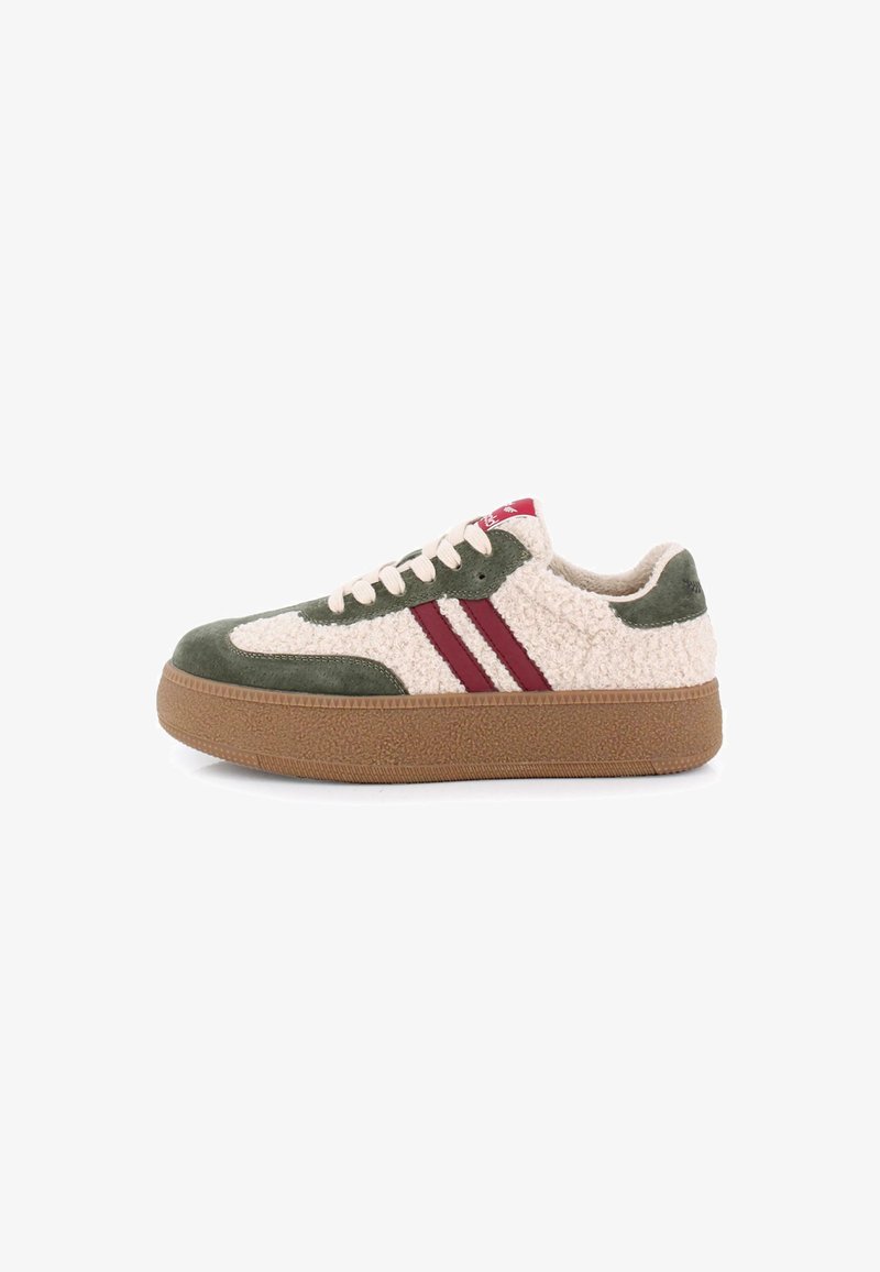 Zapatillas de ante verde y tela texturizada crema con rayas rojas, cordones crema y suela de goma marrón. La suela de goma tiene un dibujo en el relieve.