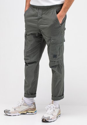 Cargo broek in donkergrijs, met een elastische tailleband, twee zijzakken en een klein patchlogo op het linkergedeelte van de pijp. Opgerolde manchetten.