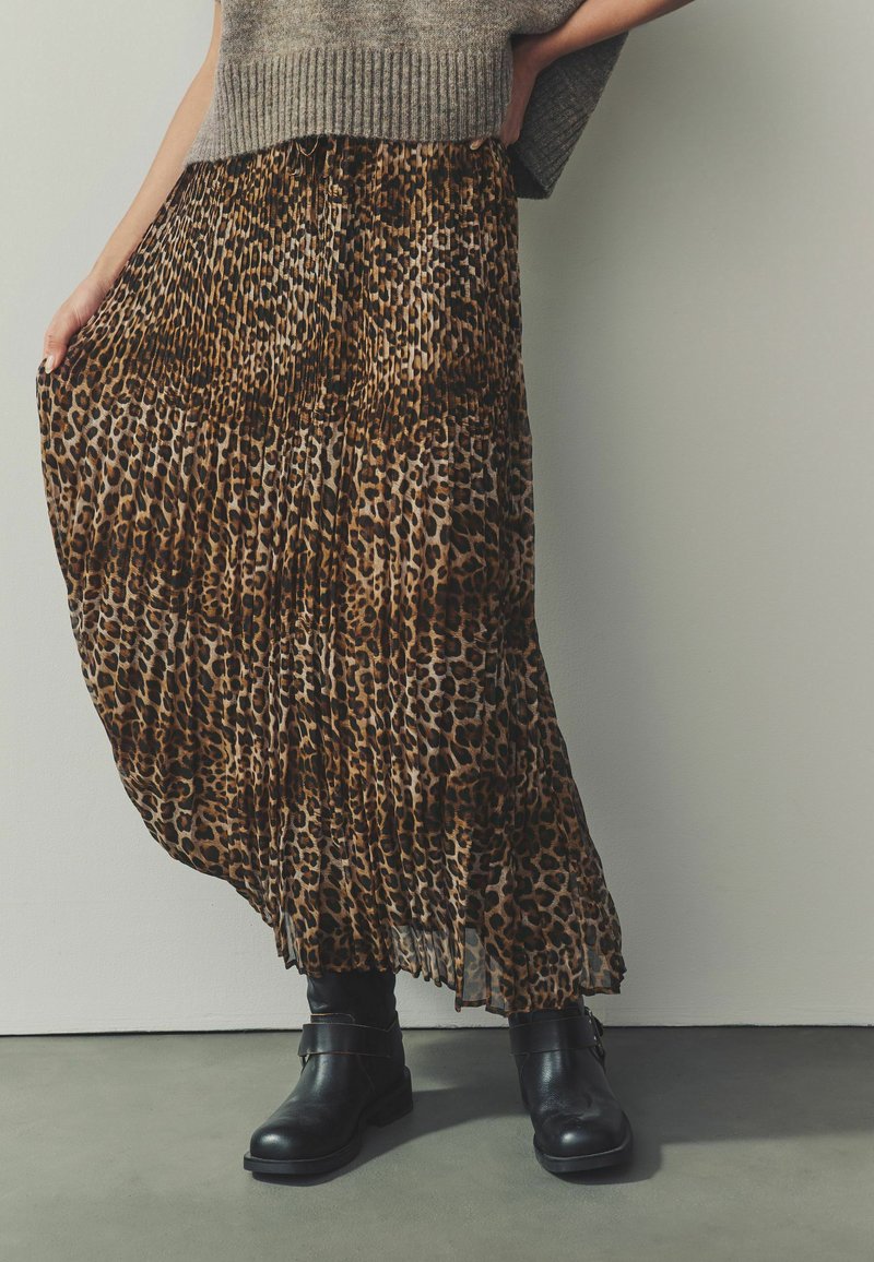 Maxi sukně s leopardím potiskem a sklady, vyrobená z lehkého materiálu, ve spojení s černými kotníkovými botami s akcentem pásku.