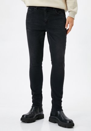 Jean slim noir avec une coupe ajustée, doté d'un design classique à cinq poches, avec un léger délavage et un mélange de coton et d'élasthanne pour plus d'élasticité et de confort.