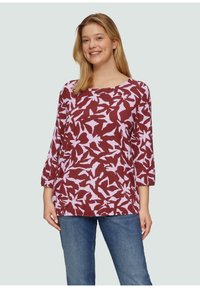 Langsleeve bordeaux top met een bloemenpatroon in roze, met een ronde halslijn en een ontspannen pasvorm. Gepaard met blauwe jeans, wat een casual uitstraling geeft.