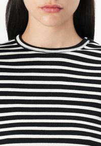 Top de malha com riscas em preto e branco, com um decote redondo, apresentando riscas horizontais de largura igual e um tecido texturizado.