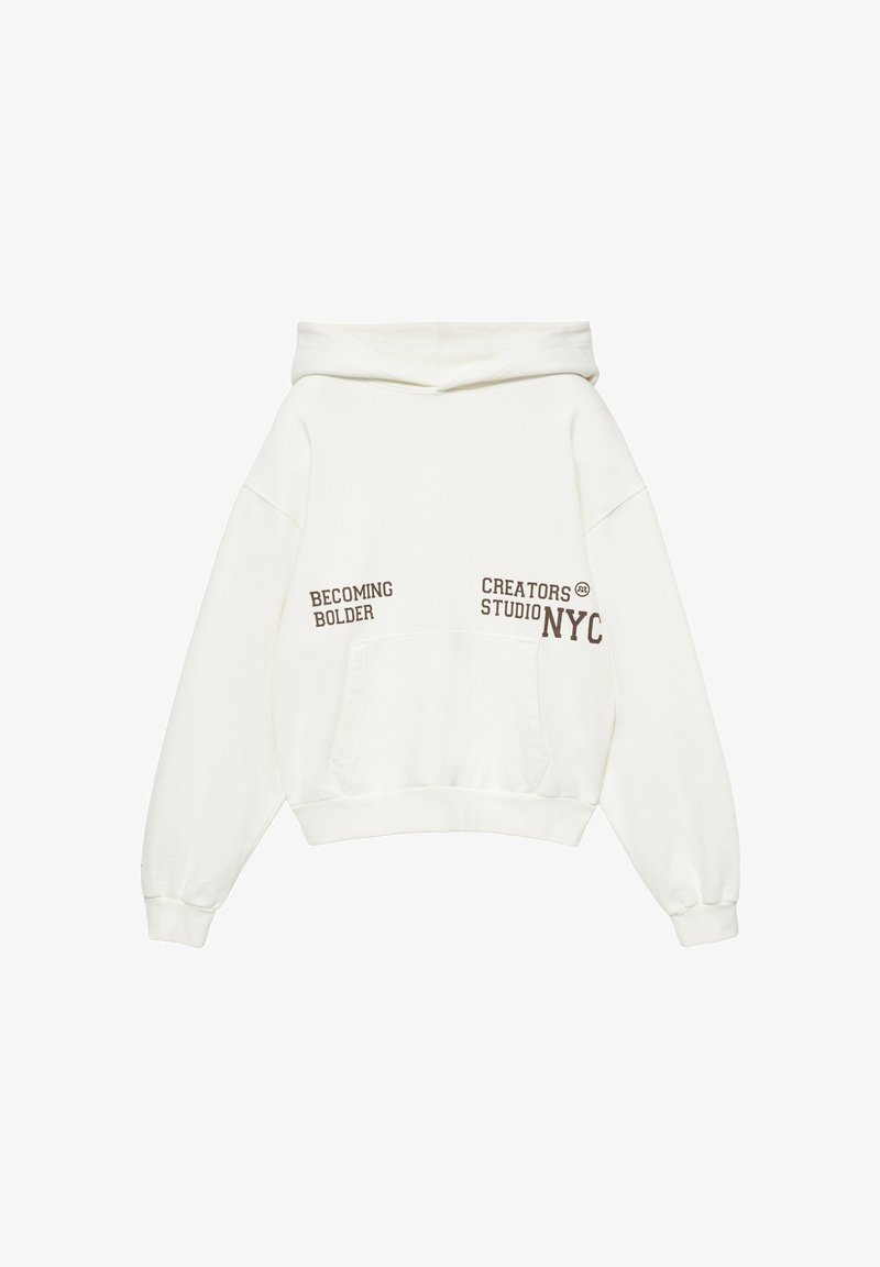 Sweat à capuche blanc avec poche avant et texte marron indiquant "BECOMING BOLDER" et "CREATORS STUDIO NYC" sur le devant.