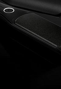 Appareil électronique noir présentant une finition lisse et mate avec un panneau texturé. Contient un bouton d'alimentation circulaire sur un côté.