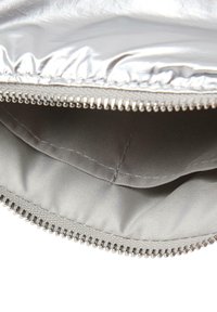 Stříbrné kovové pouzdro s hladkým povrchem, zapínáním na zip a měkkou vnitřní podšívkou. Má odolný zip s malými kovovými zoubky.