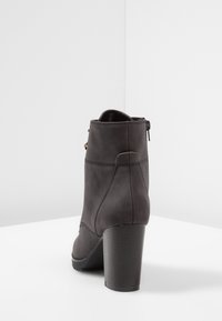 Botas de cuero negras hasta el tobillo con tacón cuadrado, que presentan un cierre lateral y detalles de costura mínimos. Textura suave con un brillo sutil.