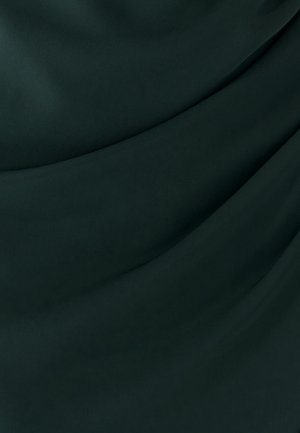 Tamsiai žalia medžiaga su lygiomis, banguotomis raukšlėmis, akcentuojančiomis tekstūrą ir subtilius šviesos atspindžius.