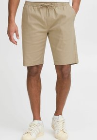 Khaki shorts dalam campuran kapas, dilengkapi dengan pinggang elastis dan tali serut, saku samping, serta potongan lurus. Dipadukan dengan sepatu sneaker putih.