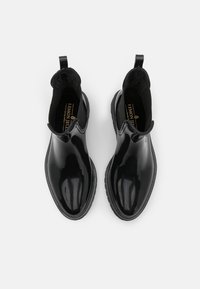Botas Chelsea de goma negras con un acabado suave y brillante. Cuenta con lados elásticos y una lengüeta para facilitar poner y quitar. Suela texturizada para mayor agarre.