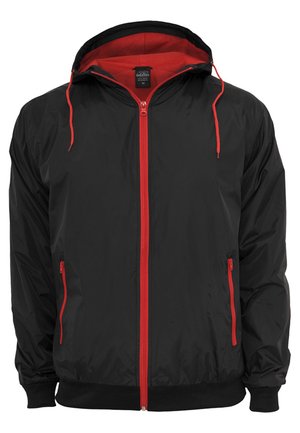 Chaqueta negra con un forro interior rojo y cremallera. Cuenta con cremallera roja y cuerdas, dos bolsillos laterales con cremalleras y puños acanalados.