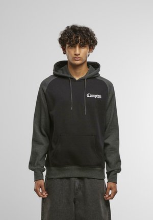 Sort og mørkegrå hoodie med en front kangaroo lomme, snørret hætte og "Compton" tekst på brystet i hvid skrift.