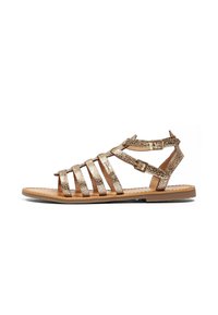 Sandal in pelle con impressioni dorate, dotata di più lacci orizzontali, fibbia alla caviglia, suola piatta e design con punta aperta. Footwear estivo classico.