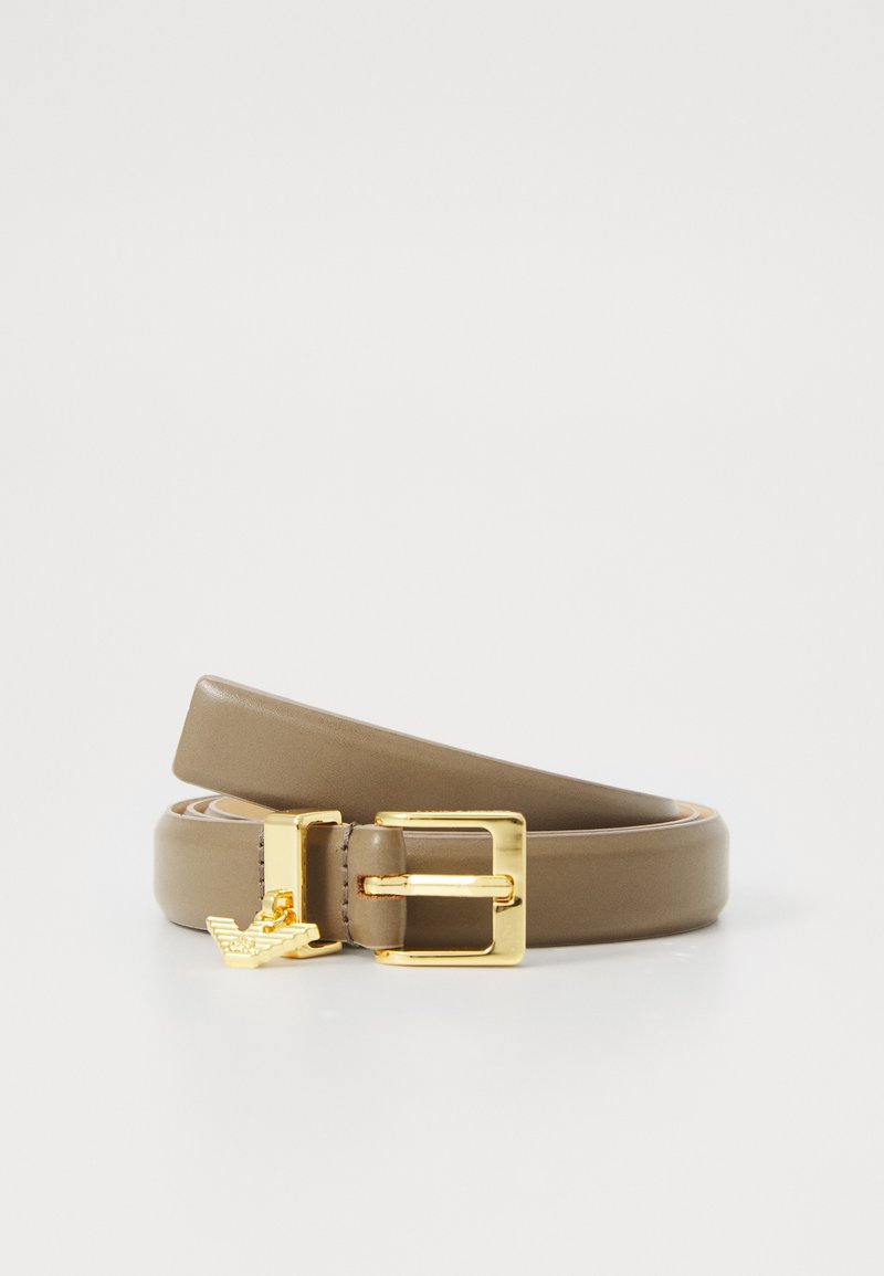 Ceinture en cuir taupe enroulée avec une boucle en or et un petit charme aigle en or sur fond blanc.