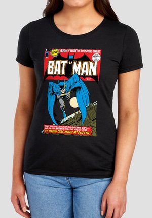 Woman wearing black t-shirt with a colorful vintage Batman comic cover showing Batman flying over Gotham City at night.