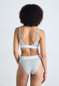 Grå bomullsbh og matchende høytlivs hipster med hvit Calvin Klein-logo på båndene. Justerbare stropper og minimalistisk design.