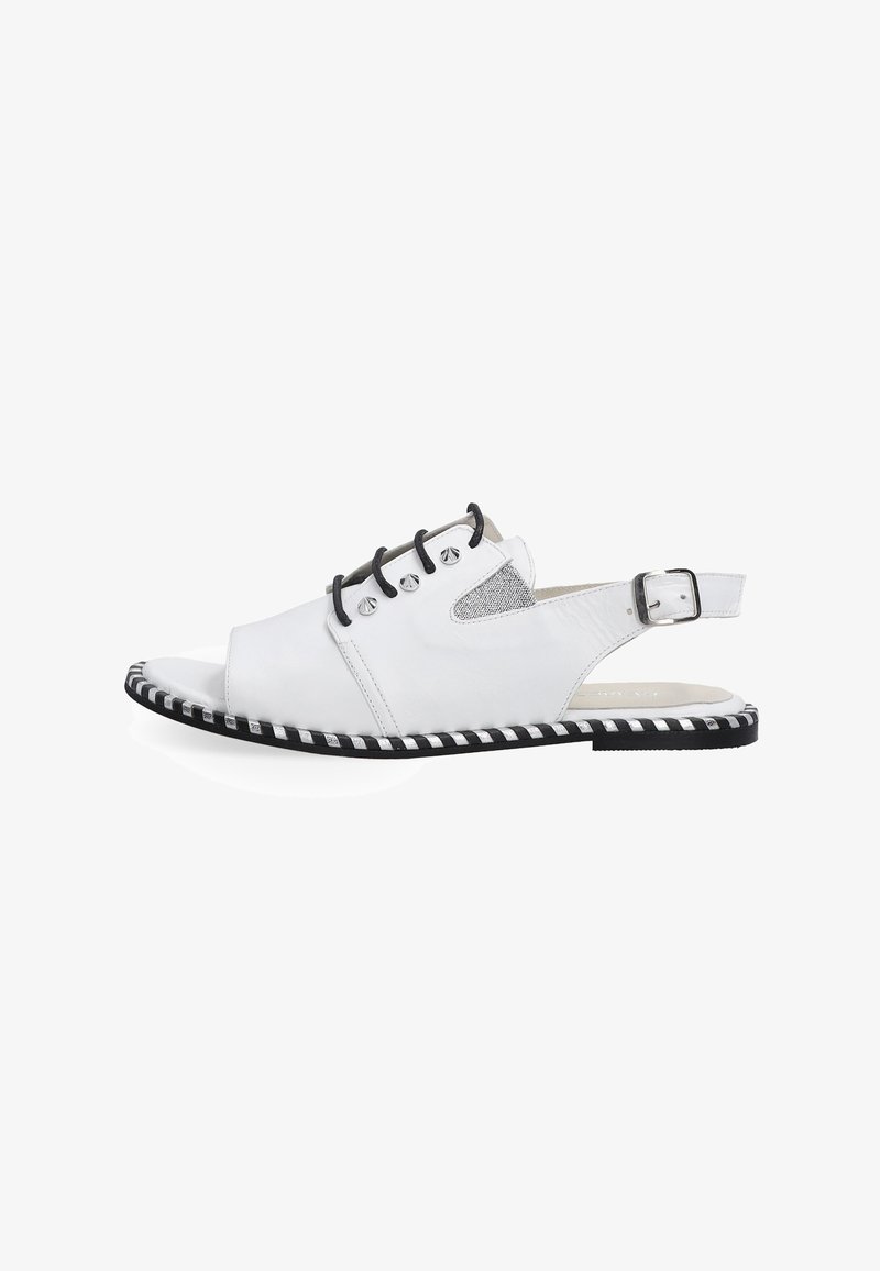 Witte leren slingback schoen met open teen, zwarte accenten, metalen gaatjes en een gestreepte zwart-witte zool. Textuurdetail aan de zijkant zichtbaar.