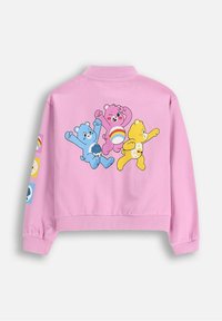 Różowa krótka kurtka z ilustracjami kreskówkowych misiów na plecach i kolorowymi naszywkami na rękawach. Gładki materiał i luźny krój.