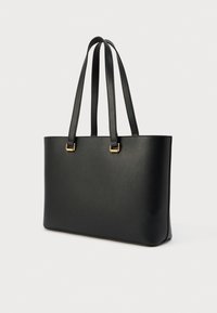 Μαύρη τσάντα ώμου από δέρμα με δύο μακριές λαβές και χρυσούς μεταλλικούς διακοσμητικούς στοιχείους. Λείος υφής και ορθογώνιο σχήμα, χωρίς ορατά μοτίβα.