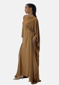 Langes braunes Kleid aus weichem Stoff, mit lockerem Schnitt, weiten Ärmeln und drapiertem Design. Schlichte, elegante Silhouette.