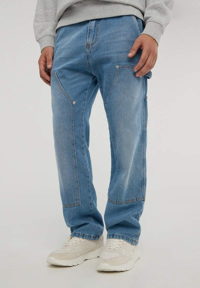 Jeans in denim azzurro chiaro con vestibilità rilassata, dotati di tasche angolate, cuciture in contrasto e dettagli hardware sottili.