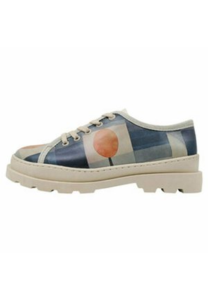 Lässiger Schnürschuh mit einem blauen und beigen geometrischen Muster, ausgestattet mit einem pinken kreisförmigen Akzent, strukturierten Sohle und abgerundetem Zehendesign.