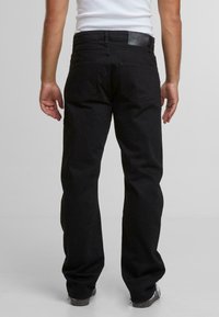 Schwarze Jeanshosen mit geradem Schnitt, ausgestattet mit einem Lederlogo auf dem Bund, zwei Gesäßtaschen und minimalen Ziernähten.